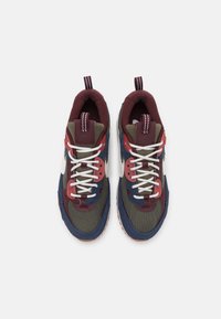 Sneaker multicolori con parte superiore in rete di colore verde oliva, bordeaux e blu navy, con lacci bianchi e accenti prominenti di rosso e blu.