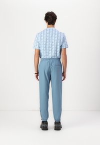  Lichtblauw kortemouwen overhemd met een geometrisch patroon, gecombineerd met lichtblauwe broek met trekkoord, voorzien van elastische boorden en zijzakken.