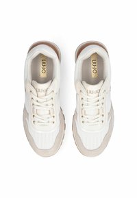 Baskets blanches avec des accents beiges et une texture en maille. Elles présentent des lacets plats, un bout arrondi et un logo sur la languette. Semelle en caoutchouc.