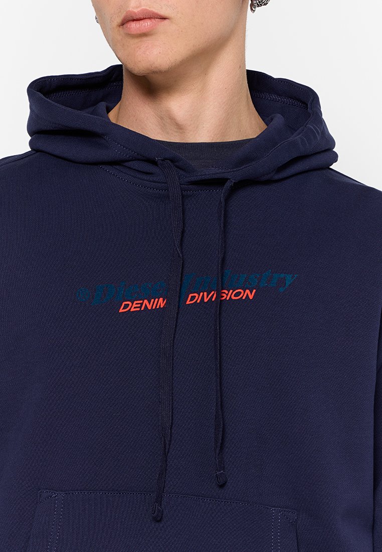 Hoodie bleu marine avec poche avant, capuche avec cordon de serrage, et texte imprimé en turquoise et rouge : "Diesel Industry Denim Division." Tissu texturé.