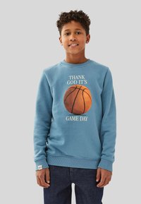 Blå sweatshirt med en basketgrafik och texten "TACK GUD FÖR ATT DET ÄR MATCHDAG." Ribbstickade mudd och nederkant, mjukt bomullstyg.