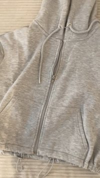Hallhalli hallidekk, millel on nööriga kapuuts, kaks eesmist taskut ja elastne äär. Omab tekstuurset kangast, millel on peen muster.