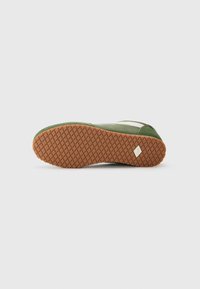 Grønne sneakers med gummisåle som har et teksturert gripe mønster, hvite sidedele og en polstret kant for komfort.