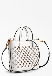 Biała skórzana torebka z wyciętym wzorem kratki, złotymi akcentami i podwójnymi uchwytami. Posiada odpinany pasek i czarne wykończenia.