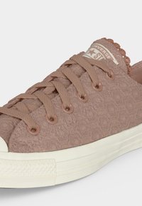 Ανοιχτό καφέ Converse sneaker με υφή, με ταιριαστά κορδόνια, μεταλλικά ρούχισματα, λευκή καουτσούκ σόλα και ετικέτα στη γλώσσα με το λογότυπο.