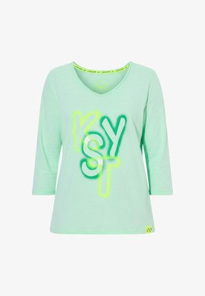 Chemise vert clair à encolure en V avec manches trois-quarts et lettres colorées superposées formant "K S Y T" sur le devant.