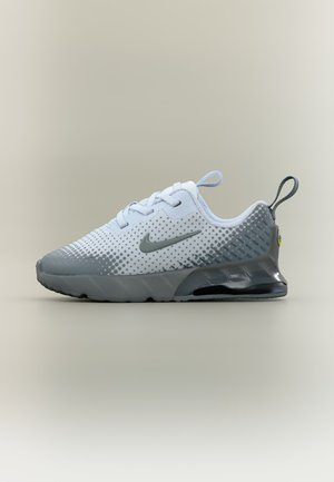 Bijela i siva Nike tenisica sa vezicama, trakama za povlačenje na peti i jeziku te vidljivom zračnom jastučićem na potplatu, prikazana u bočnom profilu.