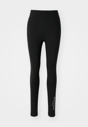 Black leggings made of stretchy fabric. High waist with smooth texture. Features white text along the lower leg saying "ATHELEISURE."