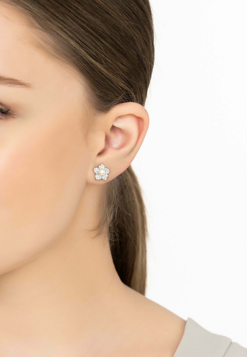 Flower-shaped stud earrings with a central pearl, surrounded by small clear stones, set in silver-tone metal.