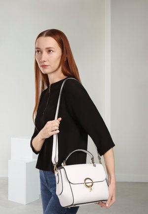 Gestructureerde handtas van wit leer met zwarte accenten, gouden beslag, bovenhandvat en afneembare schouderriem; gebogen vorm.