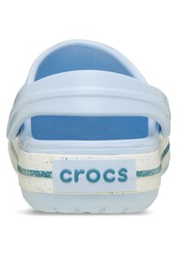 Blauwe Crocs met een transparante bovenkant, een effen blauwe voetbed, een textuur op de achterkant en een wit gespetterde zool met een teal streep en het merklogo.