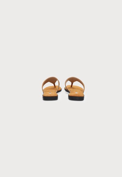 Pair of tan flat sandals with black soles and single wide straps, viewed from the back on a white background.