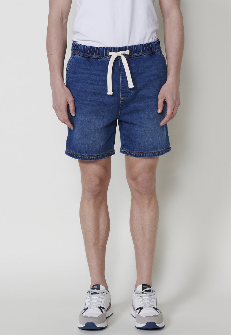 Denima šorti ar elastīgu jostu, ar auklu aizvēršanu un zilā krāsā. Iespējas ar apakšmalām un niansētām pielikšanas detaļām.