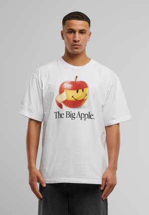 Camiseta blanca de algodón que presenta un gráfico colorido de una manzana con una sonrisa y el texto "The Big Apple" debajo en negrita y en color negro.