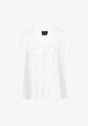 Fehér rövid ujjú blúz kerek nyakkivágással és nagy díszmasnival, amely elöl, a nyakkivágás alatt van megkötve.