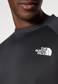 Čierne športové tričko s textúrovanou látkou, na hrudi s bielym logom "The North Face" a s okrúhlym výstrihom.