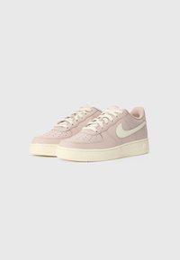 Nike Air Force 1-sko i lys rosa skinn med kremfargede detaljer, med perforert tåboks, flate lisser og teksturert gummisåle.