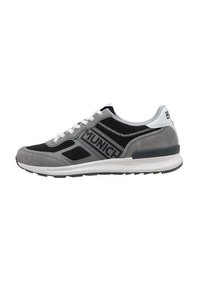 Zapatilla deportiva gris con paneles de malla negra, acentos de ante y detalles blancos. Cuenta con cordones planos y una suela de goma texturizada.