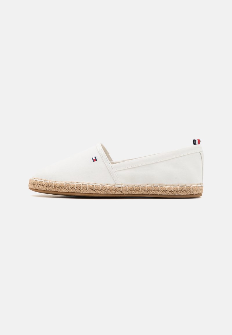 Espadrille blanche à enfiler avec semelle en jute tressé, petit logo rouge, blanc et bleu sur le côté et languette au talon, sur fond clair uni.