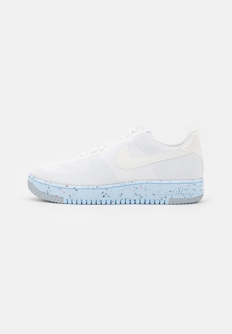 White Nike sneakers with a textured mesh upper, light blue speckled midsole, and grey rubber outsole with a ridged pattern.