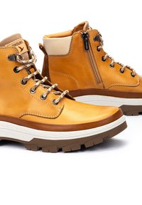Botas de tobillo de cuero marrón claro con cremallera lateral, acentos texturizados en marrón, cuello acolchado y suela de goma duradera con un pronunciado patrón de tracción.