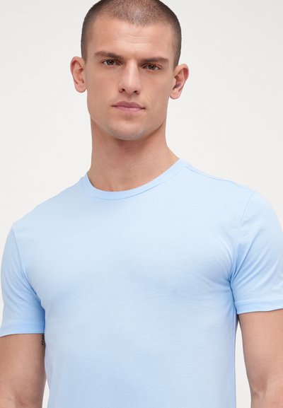 Light blue crew neck t-shirt made of soft fabric. Short sleeves and a fitted silhouette. Smooth texture with a clean design.