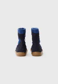 Stivali alti in suede blu con colletto a costine blu, suola in gomma marrone e lacci sui lati. Logo del marchio visibile sulla suola.