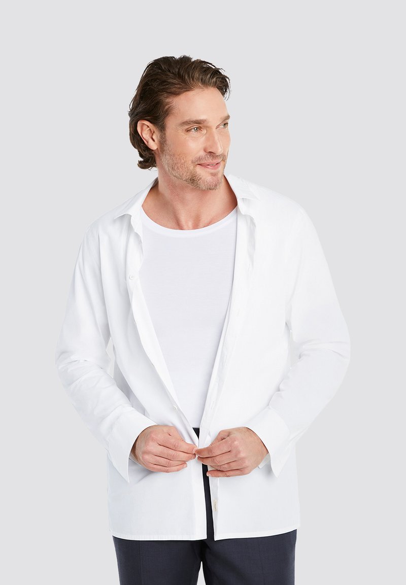 White long-sleeve button-up shirt with a soft, lightweight texture. Worn over a white T-shirt, features a classic collar and fitted design.