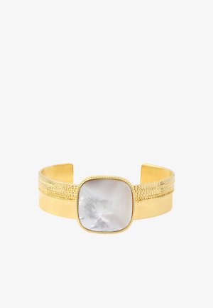 Bracelet manchette en or avec des détails texturés et une grande pierre blanche irisante et carrée en son centre.