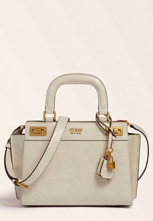 Sac à main crème à motif crocodile avec poignées supérieures, bandoulière réglable, ferrures dorées, breloque cadenas et logo "GUESS EST 1981".