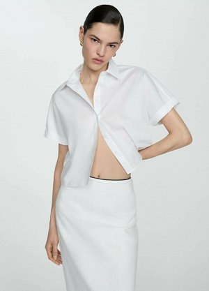 Camicia bianca a maniche corte con vestibilità morbida e parte del davanti sbottonato, abbinata a una gonna a tubino bianca. Tessuto liscio, design minimalista.