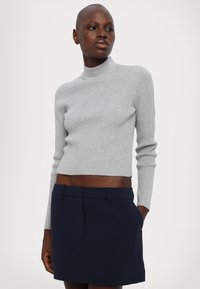 Pulover turtleneck tricotat cu nervuri gri, asortat cu o fustă ajustată de culoare bleumarin, evidențiind un design scurt și mâneci lungi.