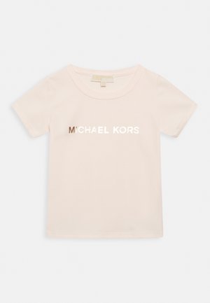 T-shirt rose pâle à manches courtes en coton doux, avec un logo métallique brillant "MICHAEL KORS" centré sur le devant.