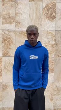 Felpa con cappuccio blu con tasca frontale e logo, abbinata a pantaloni corti neri. Tessuto morbido, vestibilità regolare e polsini a coste.