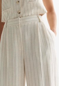 Pantalons en lin à rayures verticales beiges et bleues, taille mi-haute avec une coupe ajustée, poches avant et une ceinture structurée.