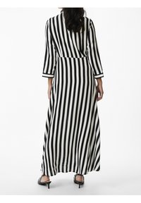 Musta-valkoinen raidallinen pitkä mekko, jossa on kolme neljäsosaa hihat, kietaisumalli, valuvat kankaat ja sileä textura.