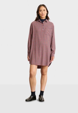 Robe chemise à carreaux rouges et bleus avec manches longues, col à boutons et fentes sur les côtés. Tissu doux avec une coupe décontractée.
