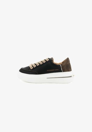Sneaker nera con tomaia liscia, lacci beige e suola spessa bianca. Presenta un pannello posteriore in brown texturizzato e una discreta dettaglio del logo.