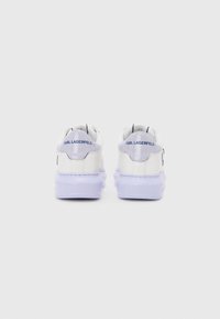 Witte leren sneakers met een paarse zool, met een ronde vorm en een logo op de hiel. Minimalistisch ontwerp met contrasterende stiksels.