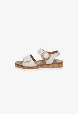 White open-toe sandal with adjustable straps, a large round buckle, cork-like sole, and white rubber outsole.