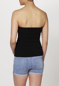 Zwart strapless topje gecombineerd met lichtblauwe spijkershorts, voorzien van een rafelige zoom en twee achterzakken. Gladde textuur, casual ontwerp.