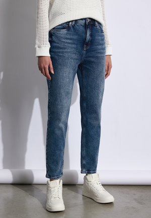Jeans en denim bleu clair avec une coupe droite, un design à cinq poches et une finition délavée, associés à des baskets montantes blanches.