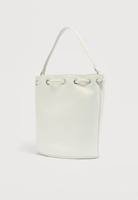 Τσάντα ώμου τύπου κάδος σε κρεμ απόχρωση με έναν ιμάντα και ασημένιες λεπτομέρειες γκρόμετ κατά μήκος της πάνω πλευράς, πάνω σε λευκό φόντο.