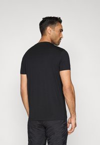 Zwart T-shirt met korte mouwen en een ronde hals. Glad katoen, losse pasvorm, nette naden en subtiel design. Draagt bij bij gepatenteerde korte broeken.