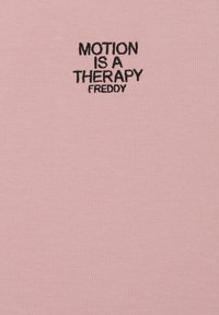 Camisa de algodón rosa con texto bordado en negro: "MOTION IS A THERAPY" sobre la palabra "FREDDY". Textura suave, escote redondo.