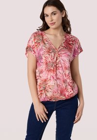 Bloemenblouse met levendige roze, rode en crèmekleuren, korte mouwen en een V-halsontwerp, gemaakt van lichte, soepel aanvoelende stof.