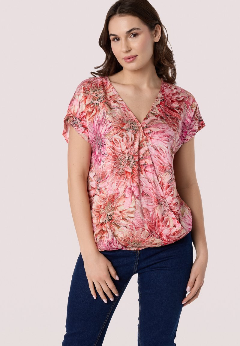 Bloemenblouse met levendige roze, rode en crèmekleuren, korte mouwen en een V-halsontwerp, gemaakt van lichte, soepel aanvoelende stof.