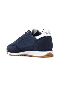 Zapatilla azul marino con upper de ante y nailon, detalles en blanco, paneles texturizados y suela de goma. Presenta una firma en el talón.