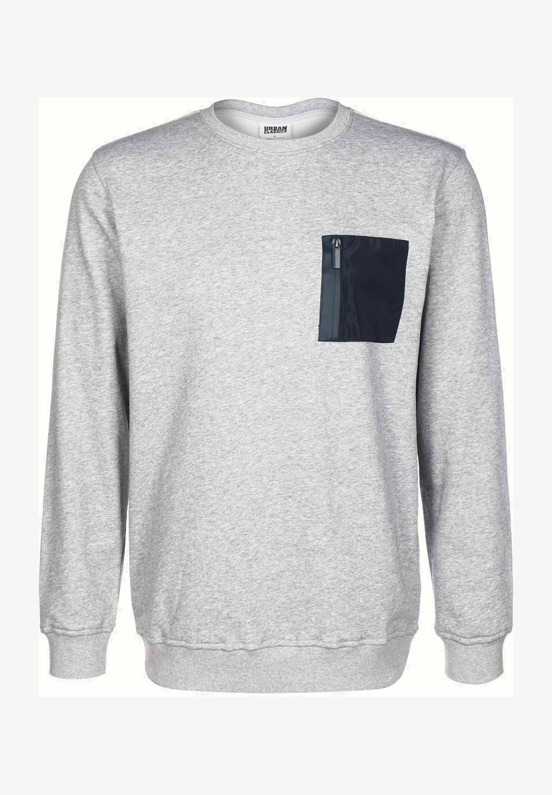 Pelēks džemperis, kas izgatavots no mīkstas auduma, ar melnu rāvējslēdzēja krūšu kabatu un ribotām piedurknēm un apakšmalu. Regulāra piegriezuma ar apaļu izgriezumu.