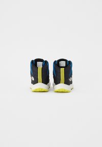 Chaussures de sport noires et bleues avec des accents jaunes. Tige en tissu texturé, semelle intermédiaire rembourrée et semelle extérieure en caoutchouc avec un motif de traction prononcé.